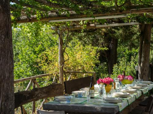 una mesa larga con platos, tazones y flores. en Villa San Leolino by Interhome, en Londa