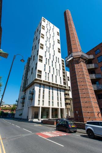 a tall white building on a street with a car at The Assembly Manchester Oasis Holding in Manchester