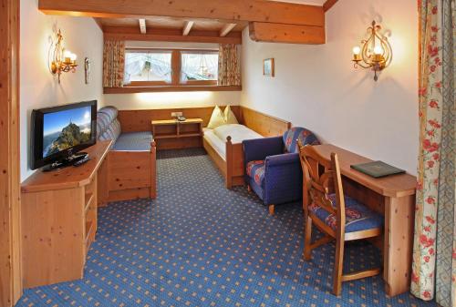 a hotel room with a television and a living room at Posthotel Erlerwirt in Erl