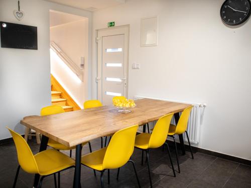 a dining room with a wooden table and yellow chairs at Ugo Apartman in Halászi