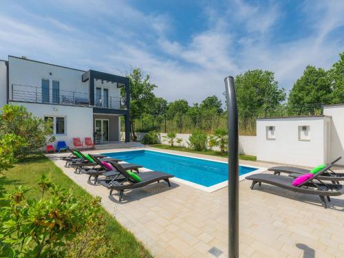 a swimming pool with lounge chairs and a house at Holiday Home Mirna - MDN156 by Interhome in Ližnjan