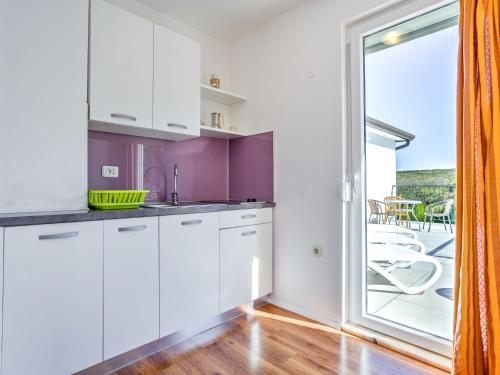 a kitchen with white cabinets and a large window at Apartment File-5 by Interhome in Zambratija
