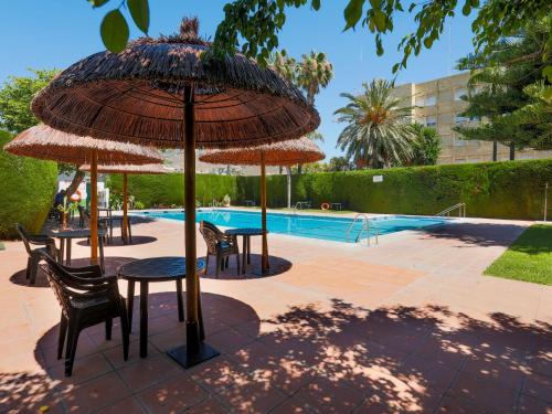 a patio with tables and umbrellas next to a pool at Apartment La Najarra by Interhome in Almuñécar