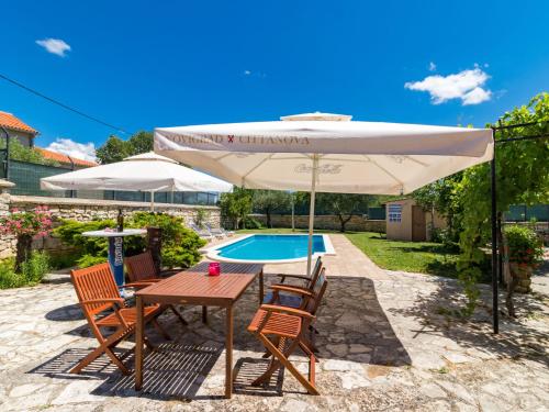 einen Tisch und Stühle unter einem Sonnenschirm neben einem Pool in der Unterkunft Holiday Home Villa San Giacomo - KST416 by Interhome in Tinjan