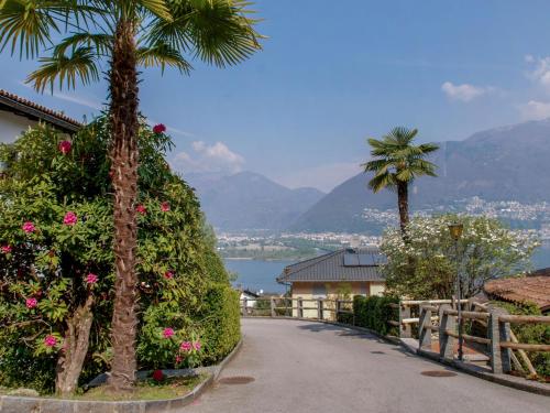 a road with palm trees and a house and a palm tree at Apartment Residence Miralago - Utoring Apt- A9 by Interhome in Piazzogna