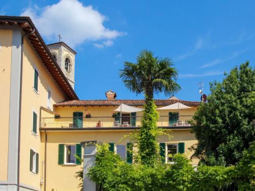 a building with a palm tree and a clock tower at Apartment Atmosfere sul lago by Interhome in Porto Valtravaglia