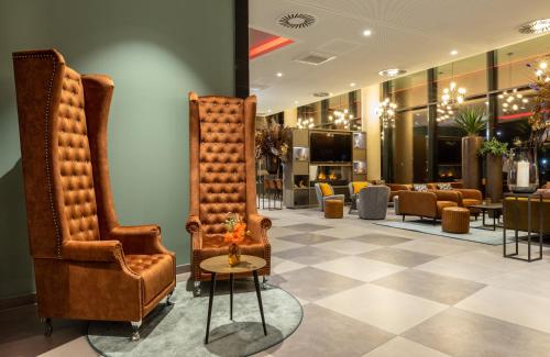 a lobby with two chairs and a barber shop at Leonardo Hotel Dortmund in Dortmund