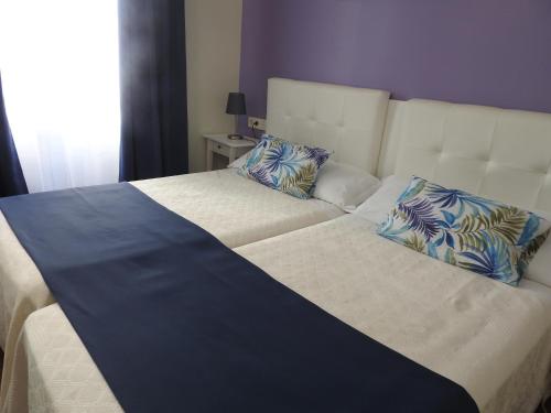 a large bed with blue and white sheets and pillows at Habitaciones Amelia in Alicante