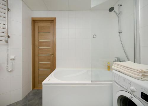 a white bathroom with a tub and a washing machine at Cozy Lootsi Residence with Sauna and Balcony - Tallinn city centre in Tallinn