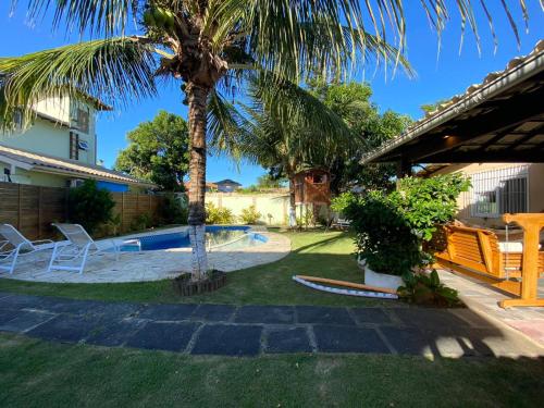 un patio con una palmera y una piscina en Búzios Beach House, en Búzios