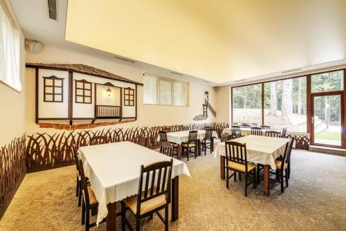 a dining room with tables and chairs and windows at Комплекс Орлово гнездо in Beli Iskar
