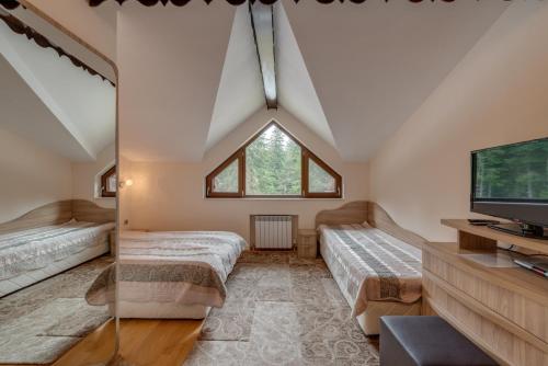 a attic bedroom with two beds and a tv at Комплекс Орлово гнездо in Beli Iskar