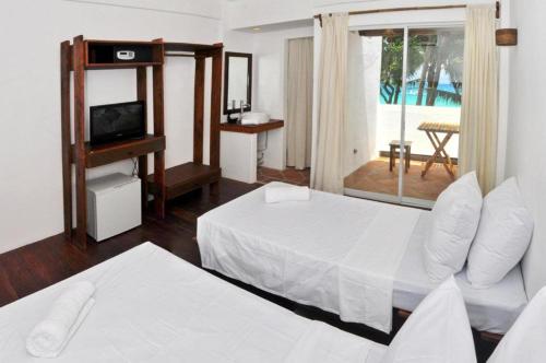 een slaapkamer met 2 bedden, een televisie en een balkon bij Boracay Coco Huts in Boracay