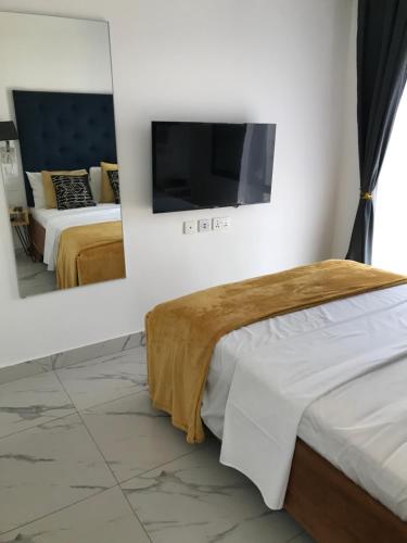 a bedroom with two beds and a flat screen tv at Mica Apartments in Sere Kunda