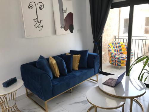 a living room with a blue couch and a table at Mica Apartments in Sere Kunda