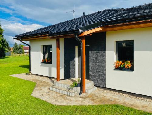 a small house with two windows and flowers on it at Apartmány DOME in Doksy