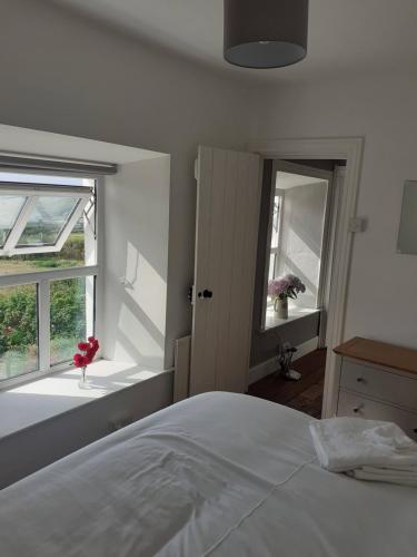 a white bedroom with a bed and a window at Gleann Loic Farmhouse in Dingle