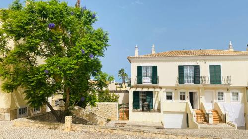 una grande casa bianca con un albero di fronte di Oliveira by Check-in Portugal a Vilamoura