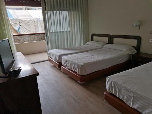 1 dormitorio con 2 camas, TV y ventana en HOTEL PARQUE PORRIÑO, en Porriño