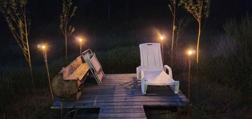 two benches and a chair on a wooden deck at night at Agroturystyka na Słonecznej Orawie u Dzikich in Jabłonka