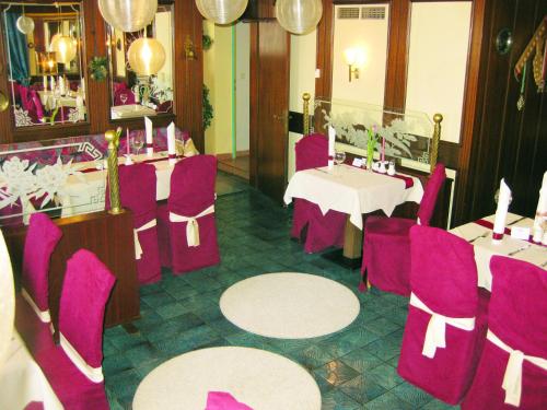 a dining room with purple chairs and tables in a restaurant at Ferienhotel Lindenhof in Leogang