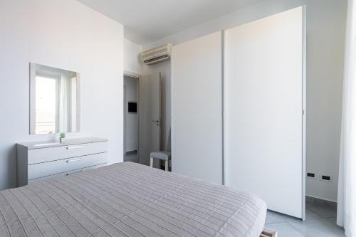 a white bedroom with a bed and a window at Terraces d'Orlando - Family Apartments with Sea View and Pool in Capo dʼOrlando