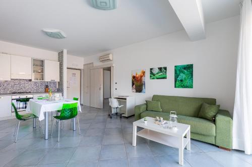 a living room with a couch and tables and a kitchen at Terraces d'Orlando - Family Apartments with Sea View and Pool in Capo dʼOrlando