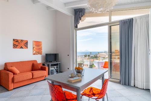 a living room with a table and a couch and a window at Terraces d'Orlando - Family Apartments with Sea View and Pool in Capo dʼOrlando