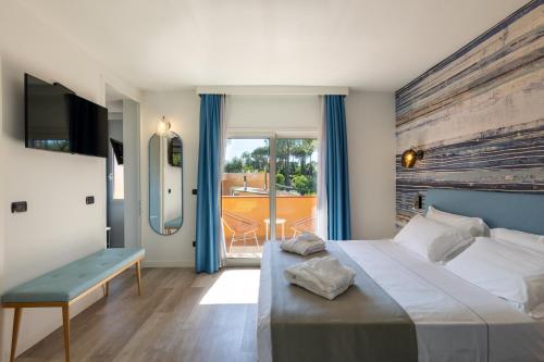 una camera con un grande letto e un balcone di Tuscany Hotel Alle Dune a Marina di Castagneto Carducci