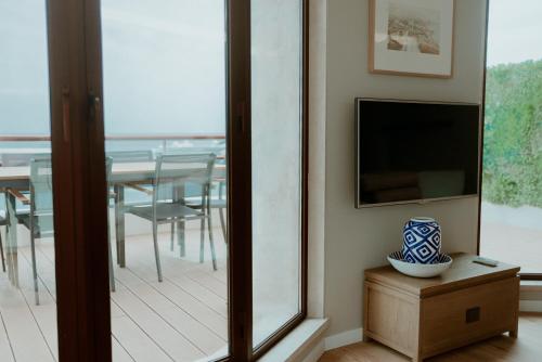 a room with a balcony with a television and a vase on a table at Rooftop Marina ll by Madeira Best Apartments in Funchal