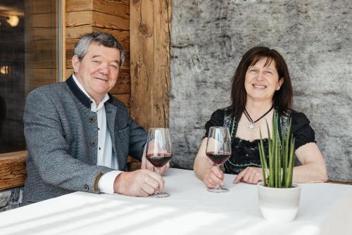 a man and woman sitting at a table with glasses of wine at Garni Ciasa Urban in Badia
