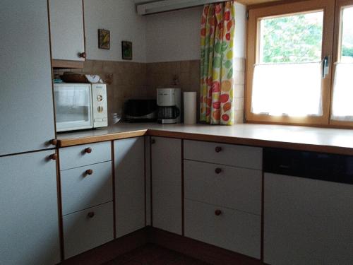 a kitchen with white cabinets and a microwave and a window at Gästehaus Maier in Kitzbühel