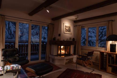 a living room with a fireplace in front of windows at Casa Nonna in Lenzerheide