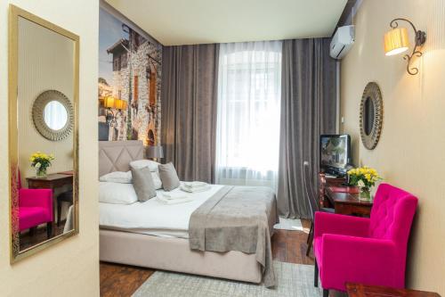 a hotel room with a bed and two pink chairs at Hotel Wenecki in Częstochowa