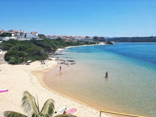 a beach with people swimming in the water at Herdade Do Freixial - Turismo Rural in Vila Nova de Milfontes