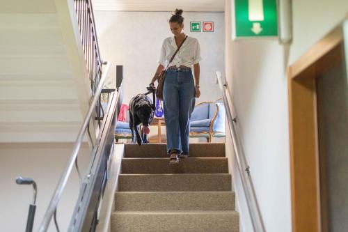 a woman walking down the stairs with her dog at Hotel L'Aretino in Arezzo