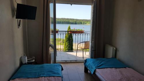 a room with two beds and a view of a balcony at RIVA Ośrodek Wypoczynkowy in Więcbork