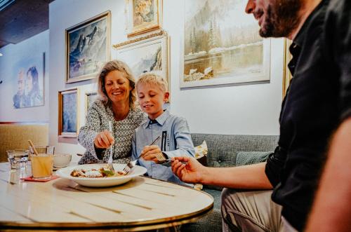 a woman and a child sitting at a table eating food at Alpenrose Bayrischzell Hotel in Bayrischzell