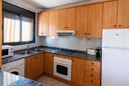 uma cozinha com armários de madeira e um frigorífico branco em Apartamentos Maribel em Calaceite