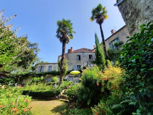 einen Garten vor einem Gebäude mit Palmen in der Unterkunft Les Cèdres in Montaigu-Vendée