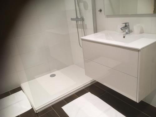een witte badkamer met een wastafel en een douche bij Residentie Jan Bart in Oostende