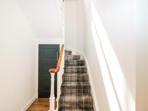 a stairway with a plaid stair runner at The Keepers Cottage at The Institute Executive Apartments in Keith