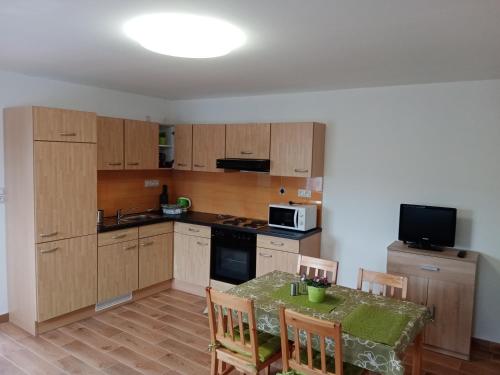 a kitchen with wooden cabinets and a table with chairs at Apartmán pod kostelem in Strážov