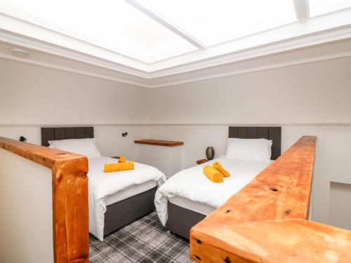 a room with two beds and a wooden table at The Marriage Room at The Institute Executive Apartments in Keith
