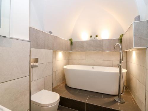 a bathroom with a white tub and a toilet at The Court Room at The Institute Executive Apartments in Keith