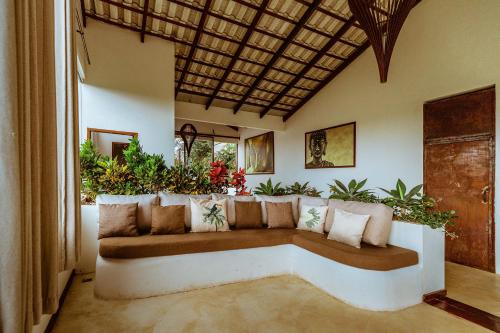 アウト・パライーゾ・デ・ゴイアスにあるPousada Casa de Shivaの植物のあるリビングルームのソファ