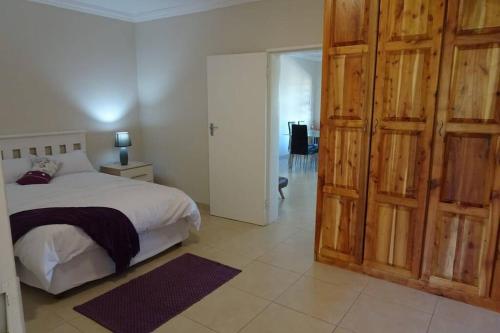 a bedroom with a bed and a large wooden door at Lovely 2-bedroom apartment with free parking on premises in Jeffreys Bay