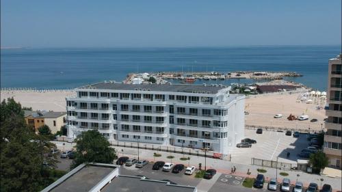 a large white building with a parking lot next to the ocean at PASHA HOTEL in Eforie Nord