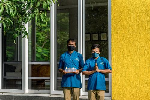 two men in blue uniforms standing in front of a building at SaffronStays Casa Manga, Karjat - pet-friendly pool villa near ND's Film World and Saltt in Karjat