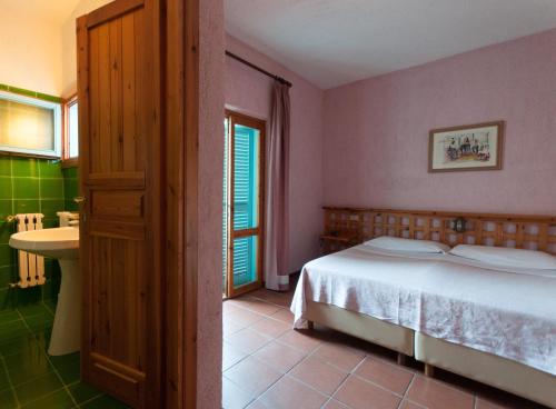 a bedroom with a bed and a bathroom with a sink at Hotel Scintilla in San Teodoro